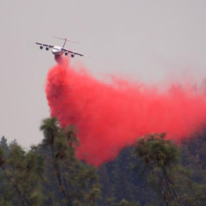 A tanker drops retardant on a wildfire.